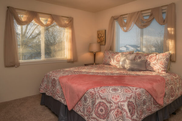 Sunlit bedroom with patterned bedding and lamp