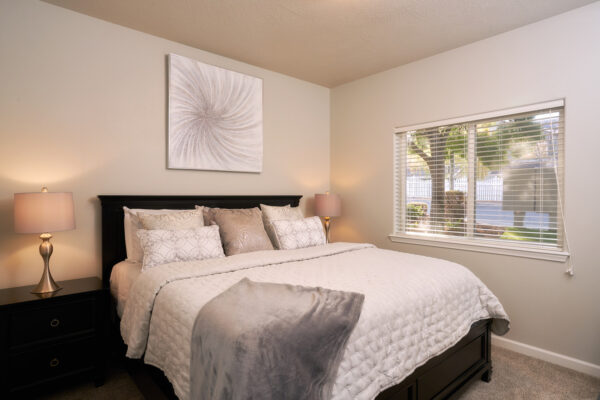 Bedroom with white bedding, nightstands, and window